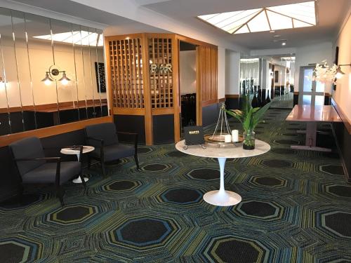 a lobby with a table and chairs on a carpet at Cascades Motor Inn in Dubbo