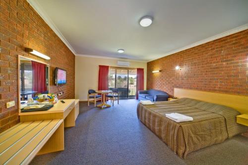 ein Hotelzimmer mit einem Bett und einer Ziegelwand in der Unterkunft Paradise Lakes Motel Shepparton in Shepparton