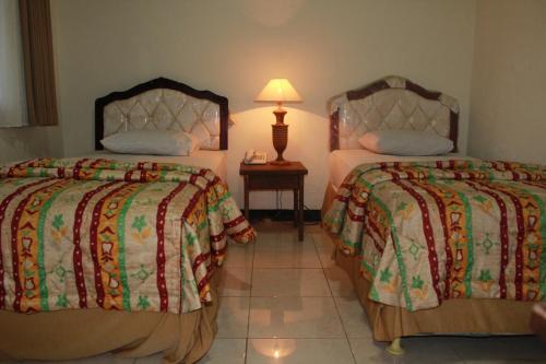 Habitación de hotel con 2 camas y mesa con lámpara en Sinar Bintang Hotel, en Padangan