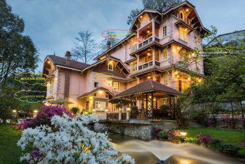 une grande maison rose avec un étang en face de celle-ci dans l'établissement Sapa Garden Bed and Breakfast, à Sa Pa