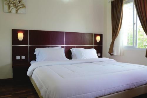 a bedroom with a large bed with white sheets at Diyar Villas Puncak M4/12 in Puncak