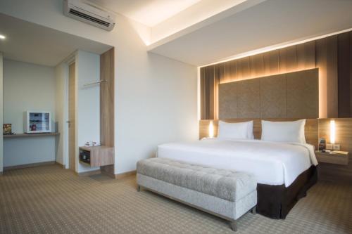 a bedroom with a large white bed and a chair at Grand G7 Hotel Kemayoran in Jakarta