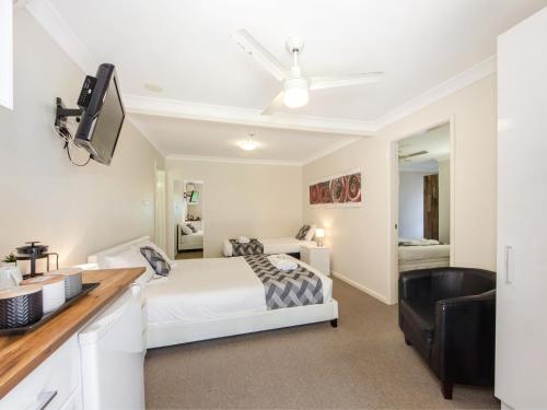 a white bedroom with a bed and a desk at Narimba Motel in Port Macquarie