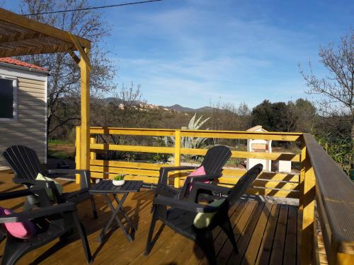 a deck with two chairs and a table on it at Lous Roussels in Le Bosc