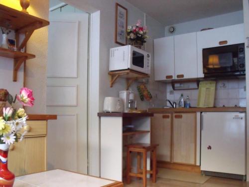 une cuisine avec des armoires blanches et un réfrigérateur blanc dans l'établissement Appartement Val Cristal, à Font-Romeu