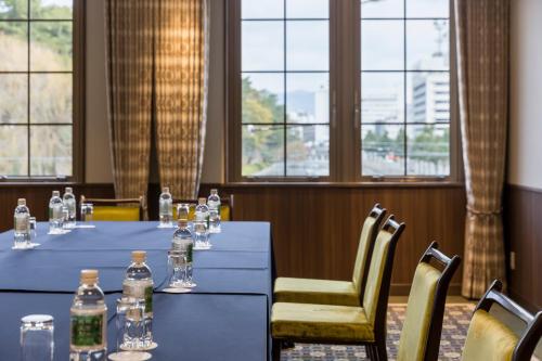 a meeting room with a table and chairs and windows at HOTEL MYSTAYS Matsuyama in Matsuyama