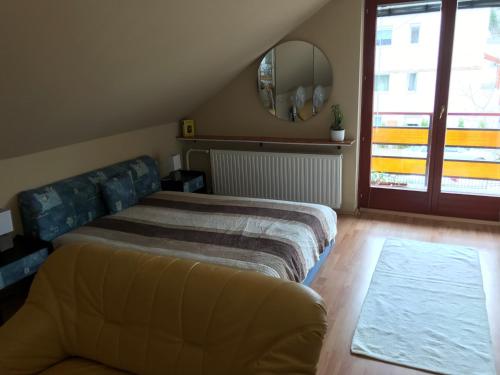 1 dormitorio con cama, sofá y espejo en Kazinczy Apartman, en Balatonalmádi