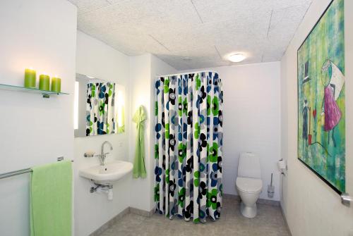 a bathroom with a sink and a toilet and a shower curtain at Caféhaven in Børglum