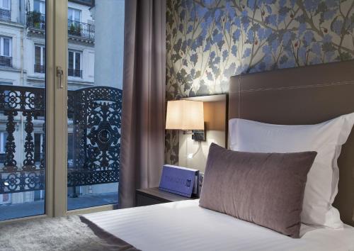 a bedroom with a bed and a window with a view at Timhotel Opéra Blanche Fontaine in Paris
