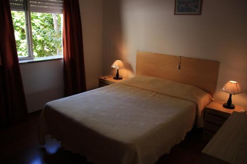 洛桑的住宿－Residencial Martinho，一间卧室配有一张床、一个窗口和两盏灯。