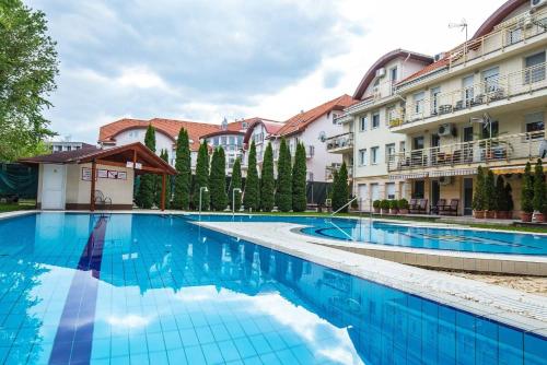 una gran piscina en un patio con edificios en Family Wellness Apartman en Hajdúszoboszló