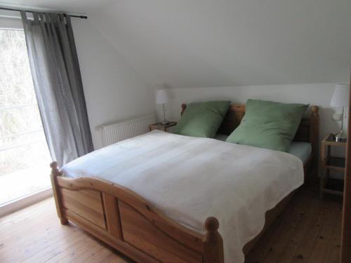 - une chambre avec un grand lit en bois et des oreillers verts dans l'établissement EIFEL Gästewohnung, à Blankenheim