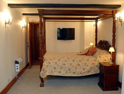 a bedroom with a canopy bed with a tv on the wall at Hopbine House in Hereford