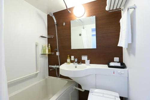 a bathroom with a sink and a toilet and a mirror at Urbain Tokyo Haneda Kamata in Tokyo