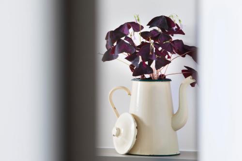 a white vase with purple flowers in it at Hôtel Les Deux Girafes in Paris