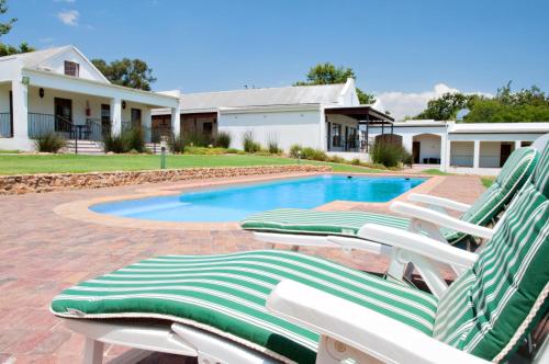 a group of lawn chairs sitting next to a swimming pool at Ongegund Lodge in Somerset West