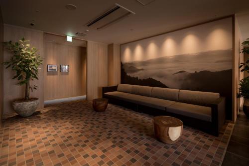 a living room with a couch and a painting on the wall at Solest Takachiho Hotel in Takachiho