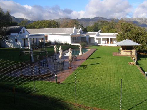 a house with a yard with chairs and a fence at Ongegund Lodge in Somerset West