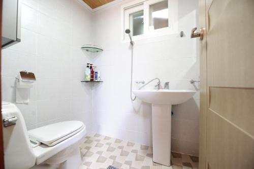 a white bathroom with a toilet and a sink at Starlight Rest Area in Jeonju