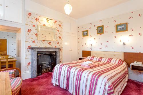 a bedroom with a bed and a fireplace at The Abbey Hotel in Tewkesbury