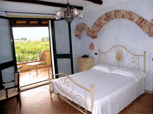 1 dormitorio con cama blanca y balcón en Agriturismo Su Canonigu, en Tortolì
