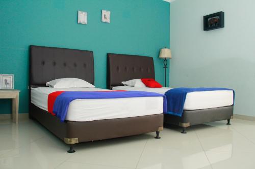 Duas camas num quarto com paredes azuis em RedDoorz @ Sersan Bajuri em Bandung