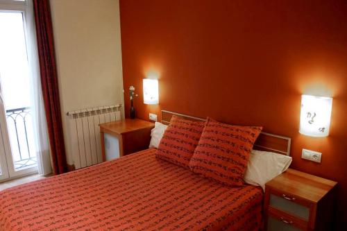 1 dormitorio con 1 cama con 2 almohadas de color naranja en Pensión Basic Confort, en San Sebastián