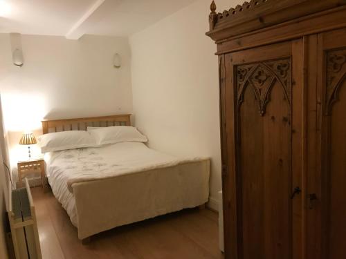 ケンダルにあるAirethwaite Houseのベッドルーム1室(ベッド1台付)、木製キャビネットが備わります。