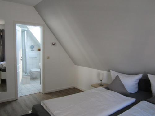 ノルダーナイにあるStrandflieder Backbordの白いベッドルーム(ベッド1台、バスルーム付)