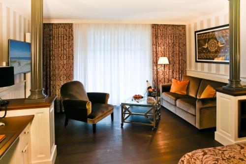 ein Wohnzimmer mit einem Sofa und einem Stuhl in der Unterkunft Europa Hotel Kühlungsborn in Kühlungsborn