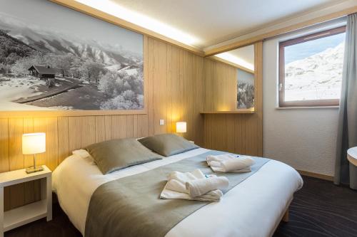 a bedroom with a large bed with two pillows on it at Hôtel Club mmv Les Bergers **** in L'Alpe-d'Huez