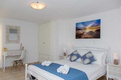 a white bedroom with two beds and a desk at Nicki's House in Agia Anna Naxos