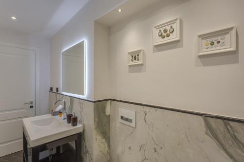 a white bathroom with a sink and a mirror at Cherubini Palace Thematic Apartment in Florence