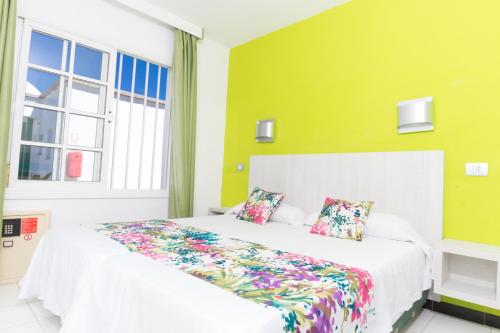 um quarto com uma cama branca e almofadas coloridas em Vista Oasis em Maspalomas