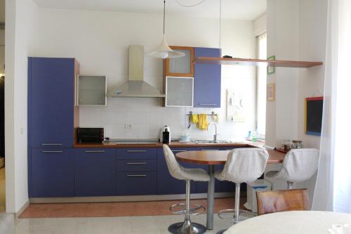 Carbonara Apartment في بولونيا: مطبخ مع دواليب زرقاء وطاولة وكراسي