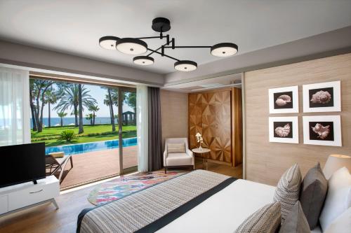 a bedroom with a bed and a large window with a pool at Acanthus Cennet Barut Collection - Ultra All Inclusive in Side