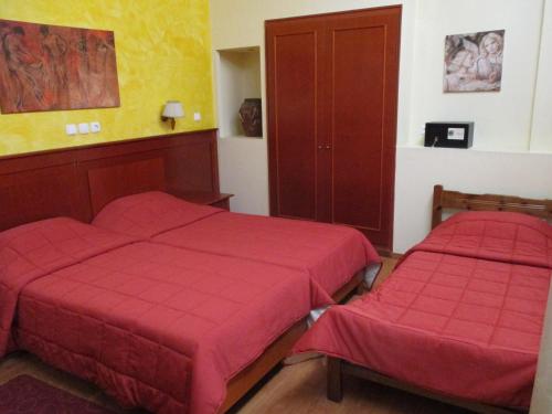 two beds in a room with red sheets at Hotel Delta in Lamía