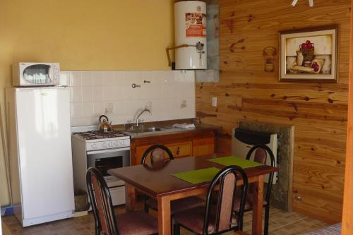cocina con mesa, fogones y nevera en Cabañas Bahía Marina, en El Calafate