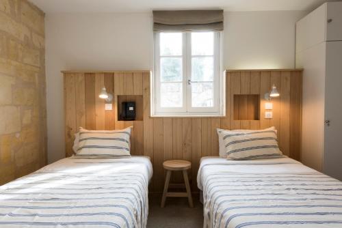 two beds in a small room with a window at Auberge de la Commanderie in Saint-Émilion