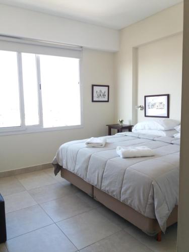 1 dormitorio con 1 cama grande y 2 toallas. en Departamento moderno centrico, vista ciudad, valle y montañas en Salta