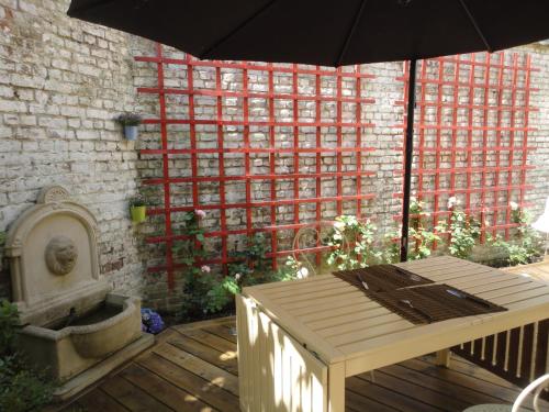 a patio with a wooden table and an umbrella at Villa Tournesol in Tournai