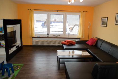 a living room with a black couch and a window at Ferienhaus Zur Edertalsperre in Edersee