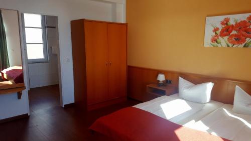 a bedroom with a bed and a cabinet and a window at Hotel Seerose in Wilhelmshaven