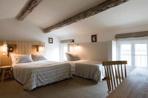 a bedroom with two beds and a table and chairs at Auberge de la Commanderie in Saint-Émilion
