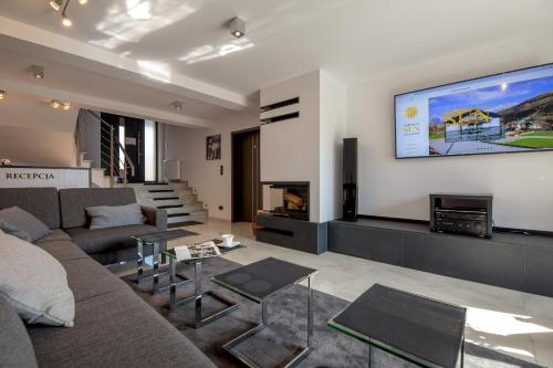 a living room with a couch and a tv on the wall at Apartamenty Sun in Szczyrk