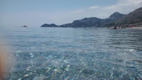 a body of water with a group of people on a beach at Polifemo in Letojanni