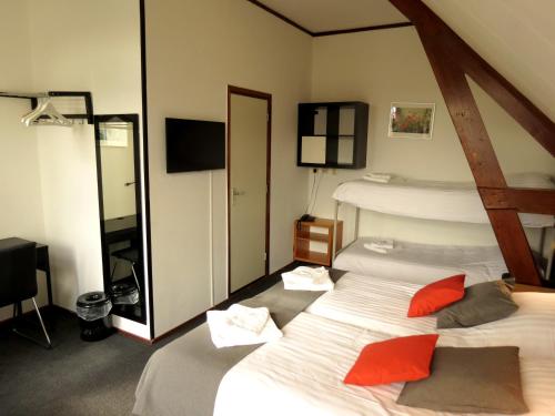 a bedroom with two beds with red pillows at Hotel Orion in Kaag