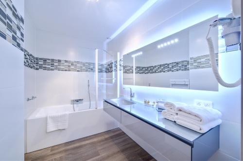 a white bathroom with a sink and a tub at Au fil de l'eau in Seneffe