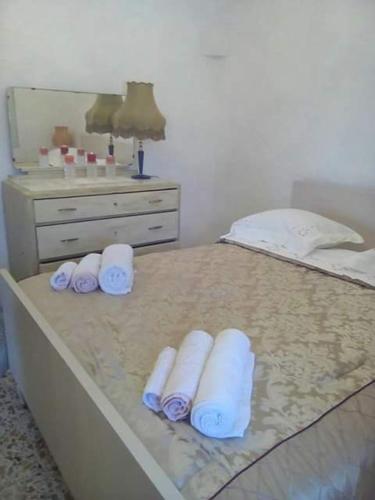 a bed with three rolled towels and a dresser at Trullo Le Tre Sorelle in Cisternino