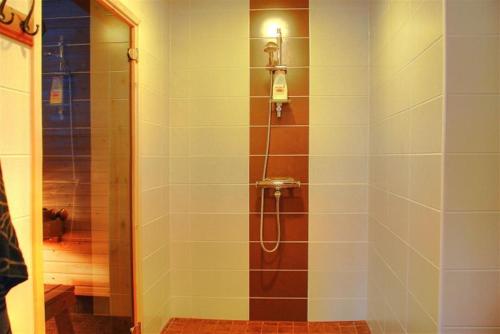 łazienka z prysznicem i ścianą wyłożoną kafelkami. w obiekcie Karkutahko Villas w mieście Ruokonen